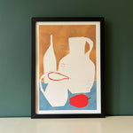 Framed abstract art print with geometric shapes on a green wall.