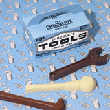 Tool shaped chocolates arranged on a blue printed background with a blue card toolbox